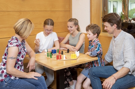 Familien beim Spielen an einem Tisch mit Sitzecke.