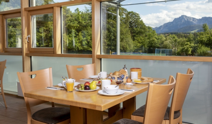 Frühstückstisch im Restaurant des Haus Chiemgau, mit Blick ins Grüne durch große Fenster.
