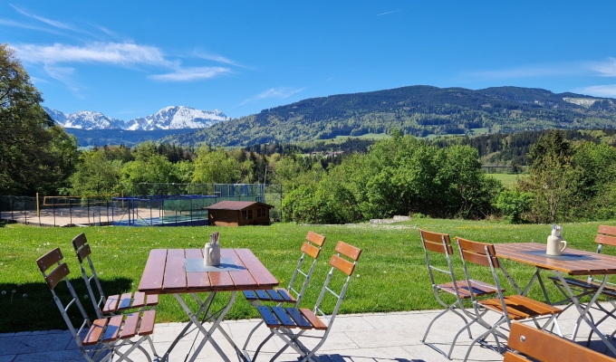 Ausblick von der Terrasse des Haus Chiemgau auf die umliegende Landschaft mit Gartenmöbeln.