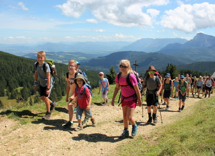 Viele Menschen beim Wandern auf einem breitem Web mit den Bergen im Hintergrund