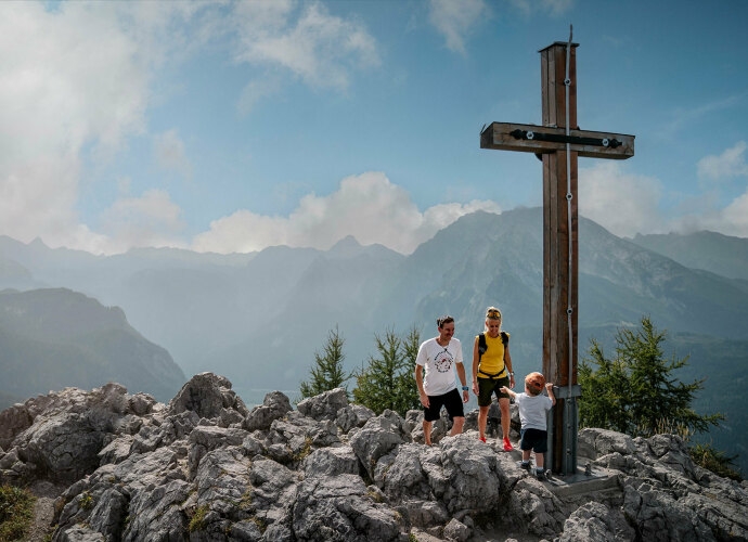 Familie am Gipfelkreuz auf einem Berg.