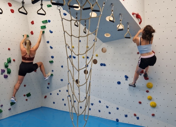 Boulderraum im Haus Chiemgau, wo zwei Frauen gerade klettern.