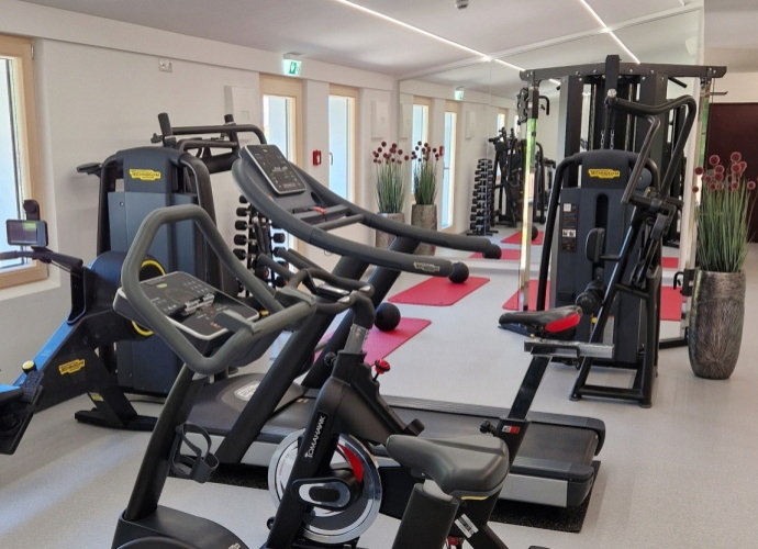 Fitnessraum mit verschiedenen Sport Geräten.