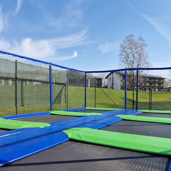 Sechsfeld-Trampolin im Außenbereich, auf dem Kinder hüpfen können.